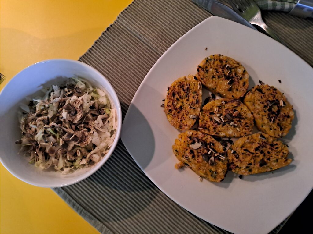 Kürbisknödelscheiben mit Kürbiskernen und Krautsalat als Beilage
