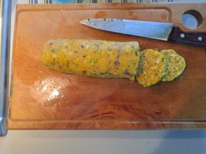 Kürbisserviettenknödel wurde bereits gar gekocht, liegt nun auf einem Schneidebrett bereit zum Schneiden