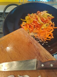 Paprika und Karotten zur Zwiebel in den Wok
