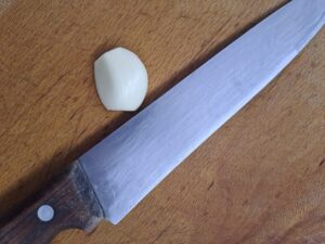 Knoblauchzehe und Messer am Brett