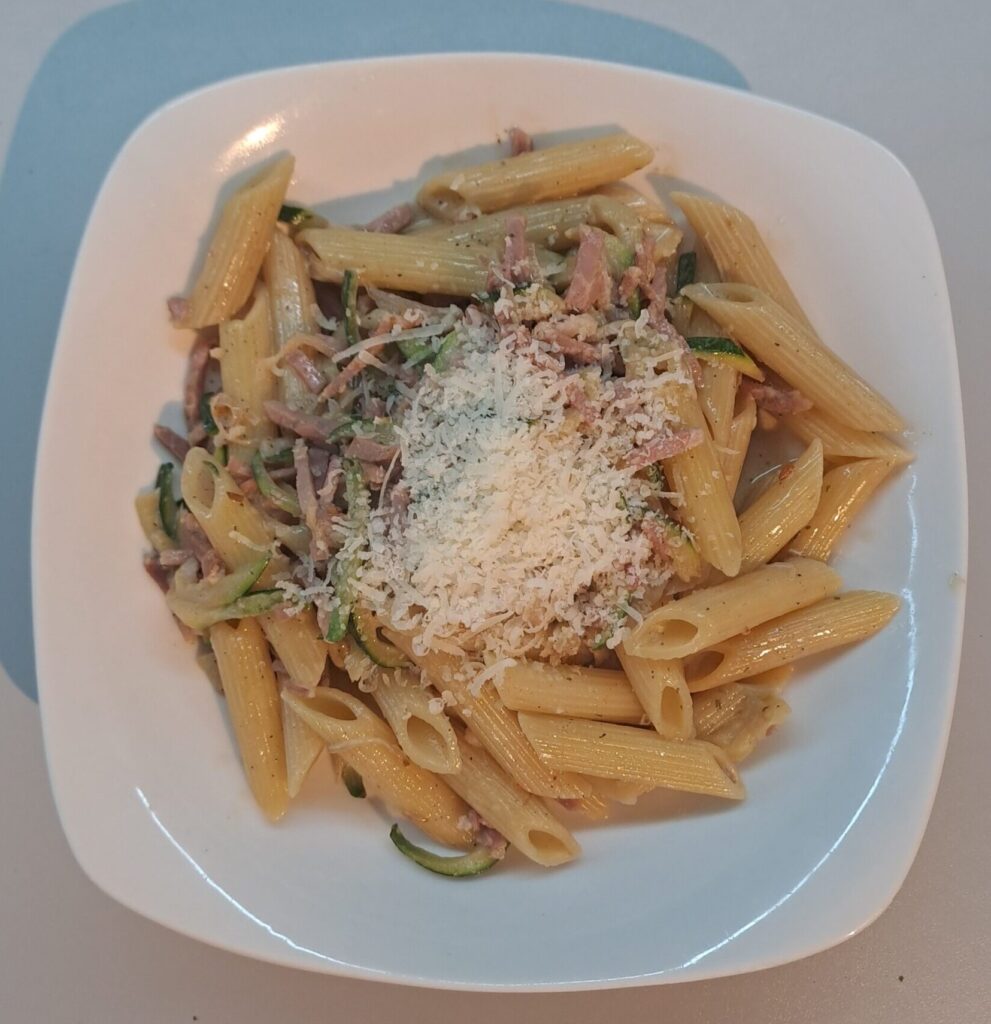 Penne mit Schinken und Zucchini, verfeinert mit Parmesankäse