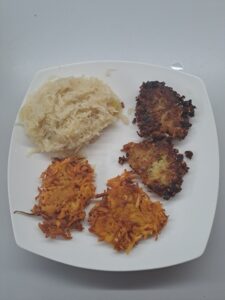 Rösti und Reispuffer mit Sauerkraut auf dem Teller angerichtet