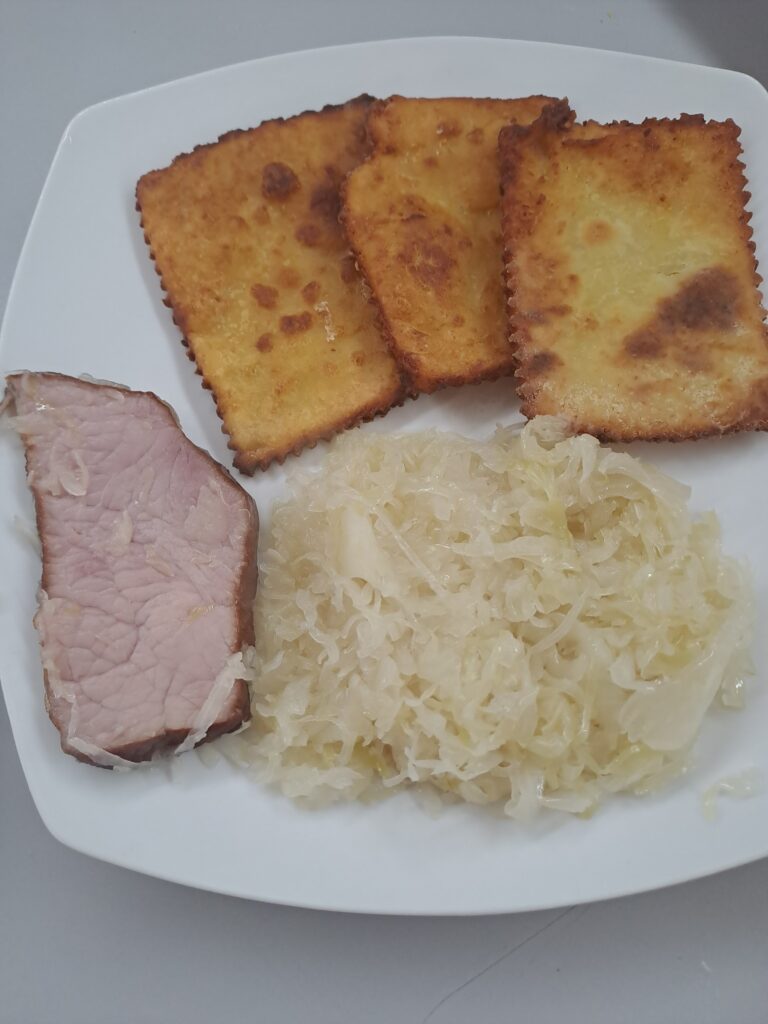 Sauerkraut mit Selchkarree und Erdäpfelblattlen angerichtet