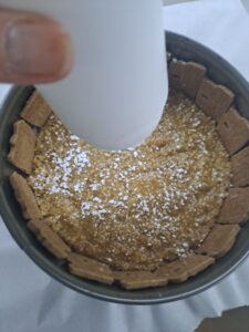 Tortenform mit Keksen und Keks-Butter-Masse zuckern