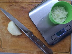 Zwiebel kleingehackt und Messer und Restzwiebel liegt am Holzbrett