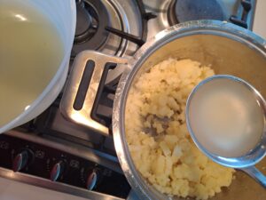 löffelweise Kartoffelwasser zum werdenden Püree