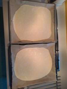 Backbleche sind mit Pizzateig ausgelegt
