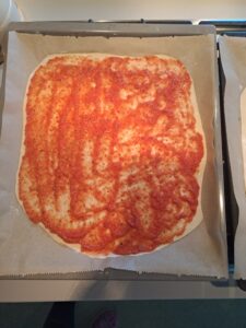 Pizzateig mit Tomatensauce belegt