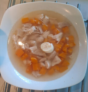 Hühnerbrühe mit Fleisch, Karotten und Wachtelei