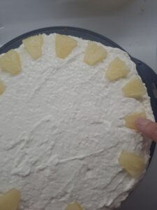 Ananasstücke auf der Torte oben verteilen