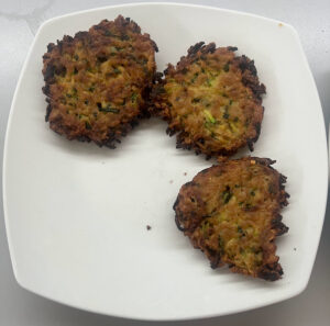 Zucchinipuffer im Teller anrichten